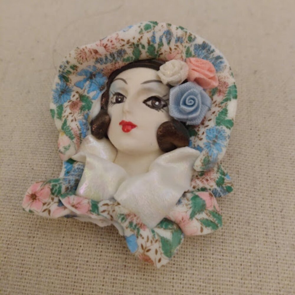 Vintage colorful lady's head brooch with floral design. Signed.